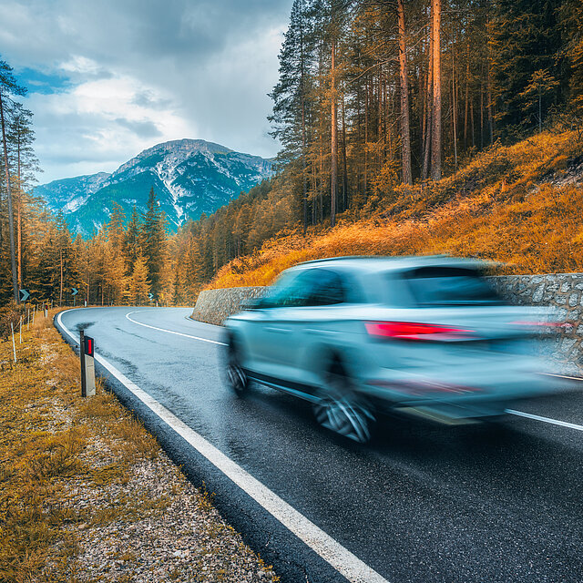 Fahrendes Elektroauto in einer Berglandschaft